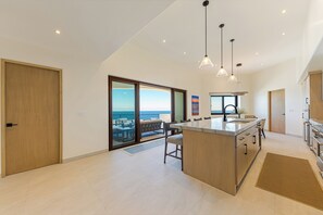 Une cuisine moderne dotée d’un grand îlot central, d’un coin repas et offrant une vue sur la mer.
