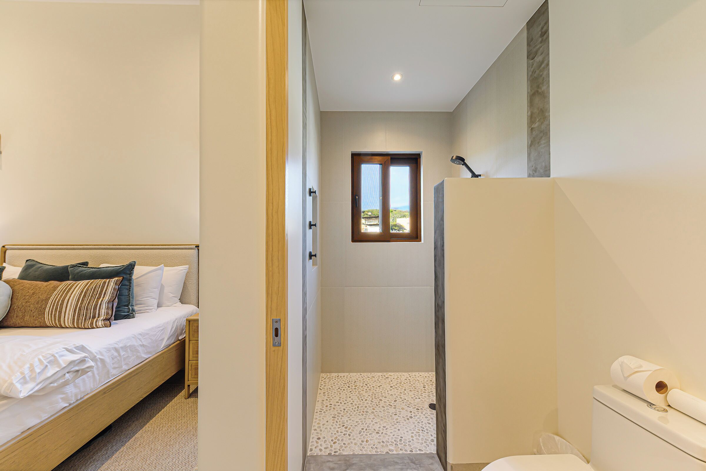 Une chambre à coucher avec un lit, une porte en bois et une vue par la fenêtre.