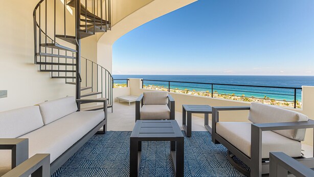 Ein Balkon mit gewölbter Decke, einer Wendeltreppe, einem Sofa, zwei Sesseln und einem kleinen Tisch.