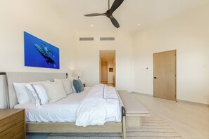 A bedroom with a bed, bedside table, ceiling fan, artwork, and a door. - Spacious 3-bedroom condo in charming San Jose del Cabo (San Jose del Cabo)