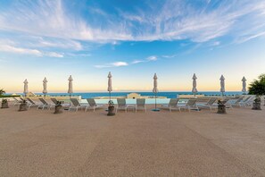 A rooftop terrace with lounge chairs and umbrellas, overlooking a pool and the sea. - Spacious 3-bedroom condo in charming San Jose del Cabo (San Jose del Cabo)