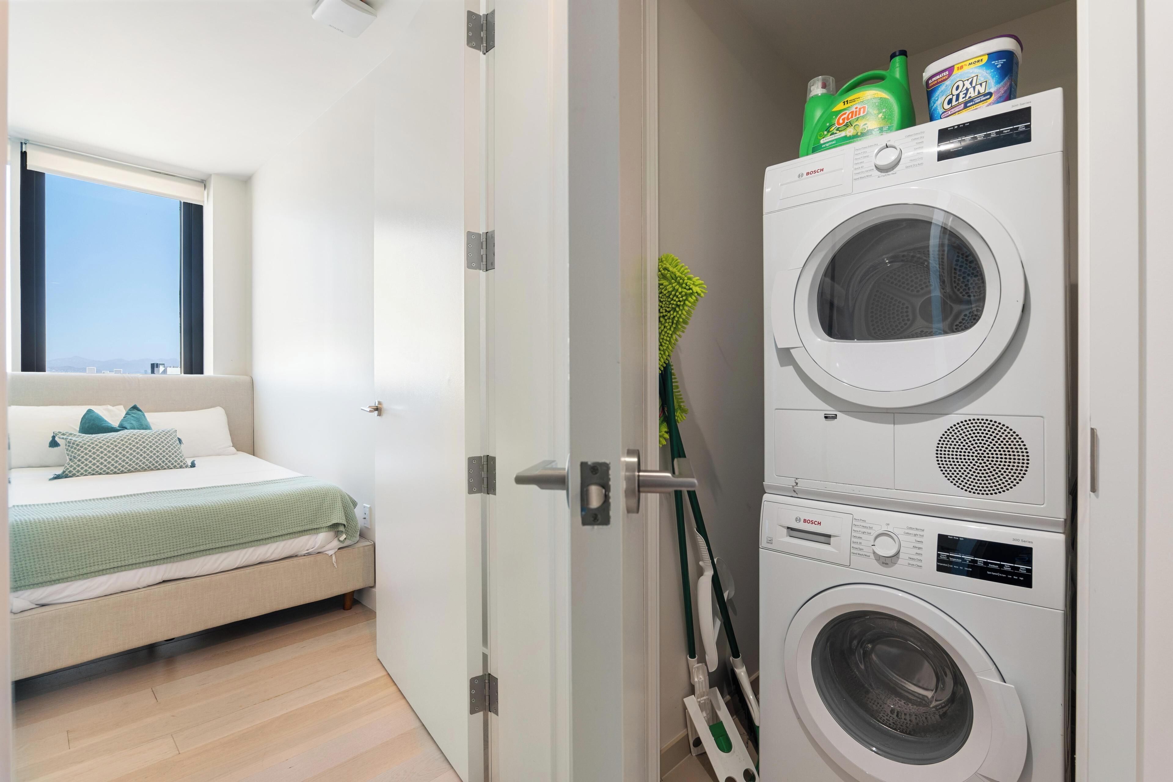 A bedroom with a bed, a window, and a washing machine unit.