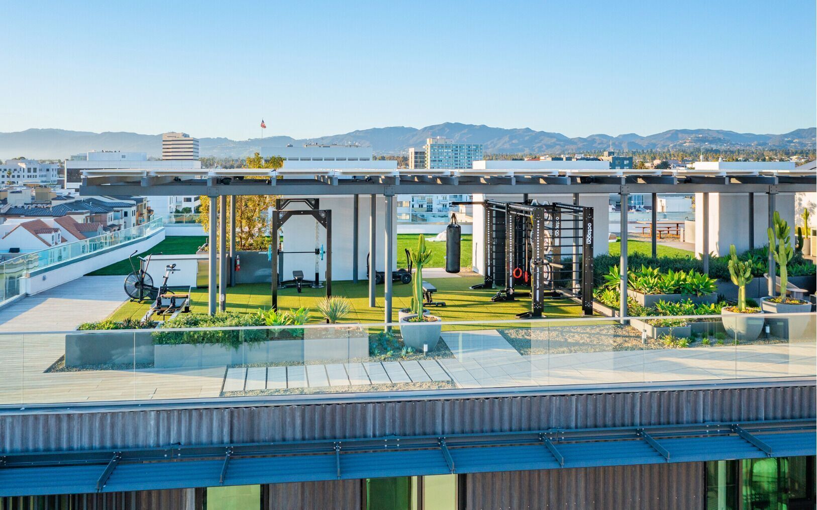 A rooftop gym with exercise equipment, a bicycle, and potted plants.