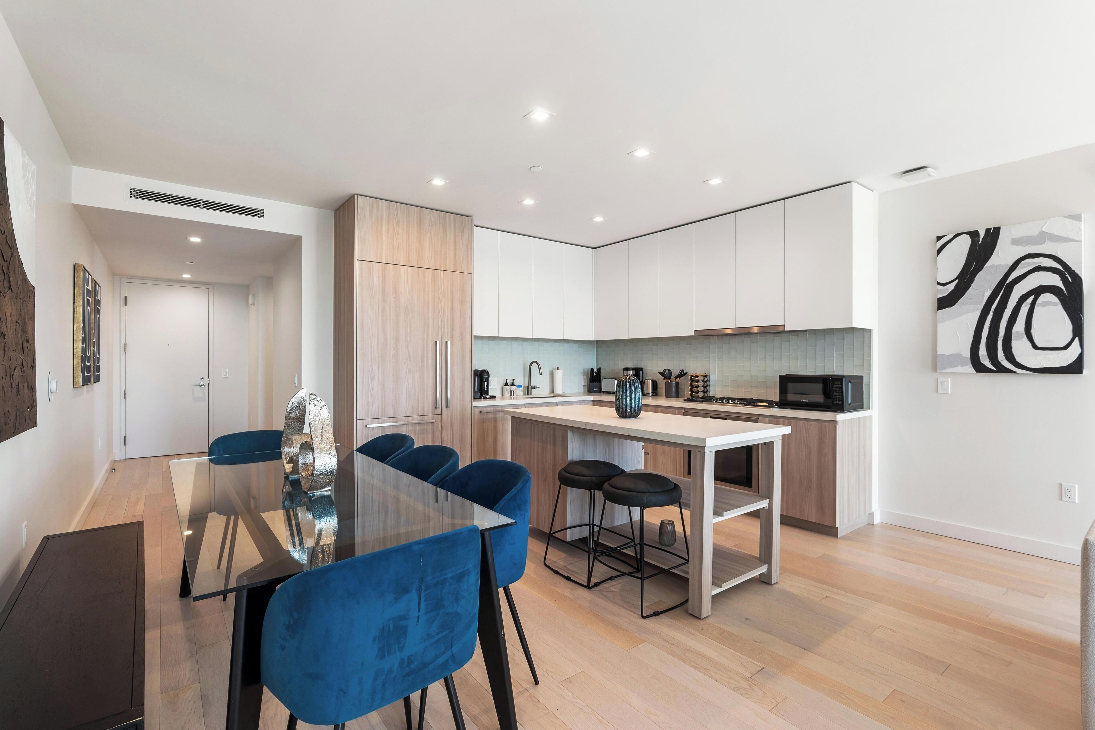 A modern kitchen with white cabinets, a central island, and a microwave.