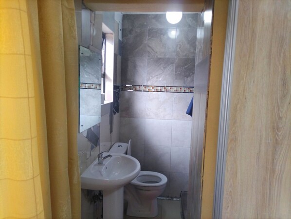 Un bagno con lavandino, WC e specchio.