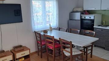 Una cocina compacta con zona de comedor, muebles de madera y una ventana con cortinas.