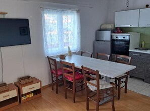 A compact kitchen with a dining area, wooden furniture, and a window with curtains.