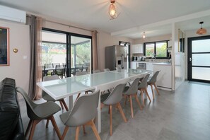 Une cuisine moderne dotée d’un îlot central, d’un coin repas avec des chaises et d’une grande fenêtre.