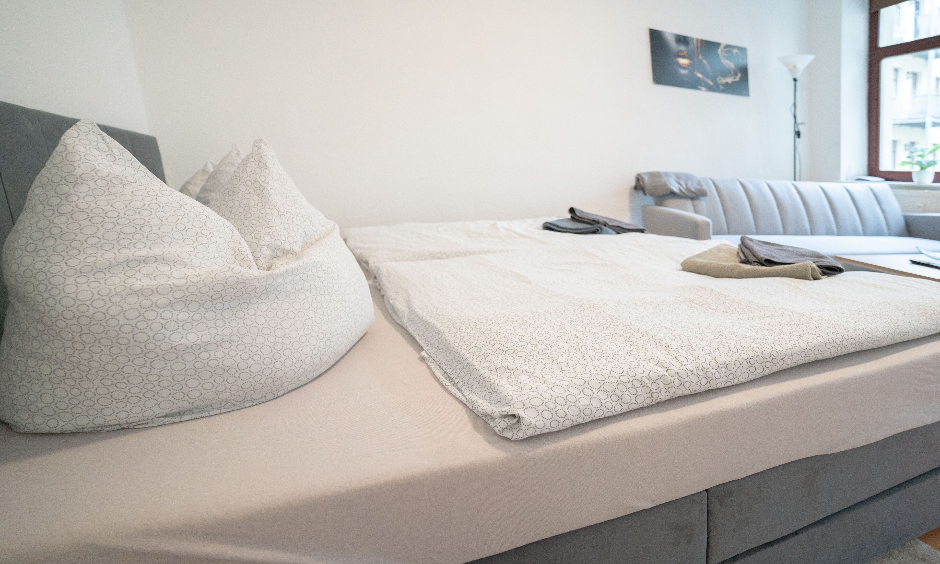 A neatly made bed with a patterned pillow and a folded blanket.