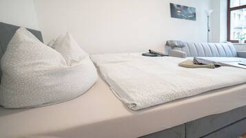 A neatly made bed with a patterned pillow and a folded blanket.