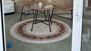 A glass door with a wicker chair and table set on a patterned rug, a 'Bienvenue' sign, and a window with a view of a building. - Semi-troglodyte and atypical house (Loches)