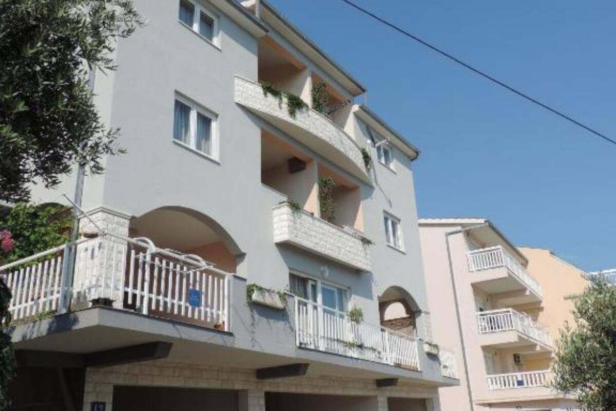 A multi-story residential building with balconies, arched windows, and a clear sky.