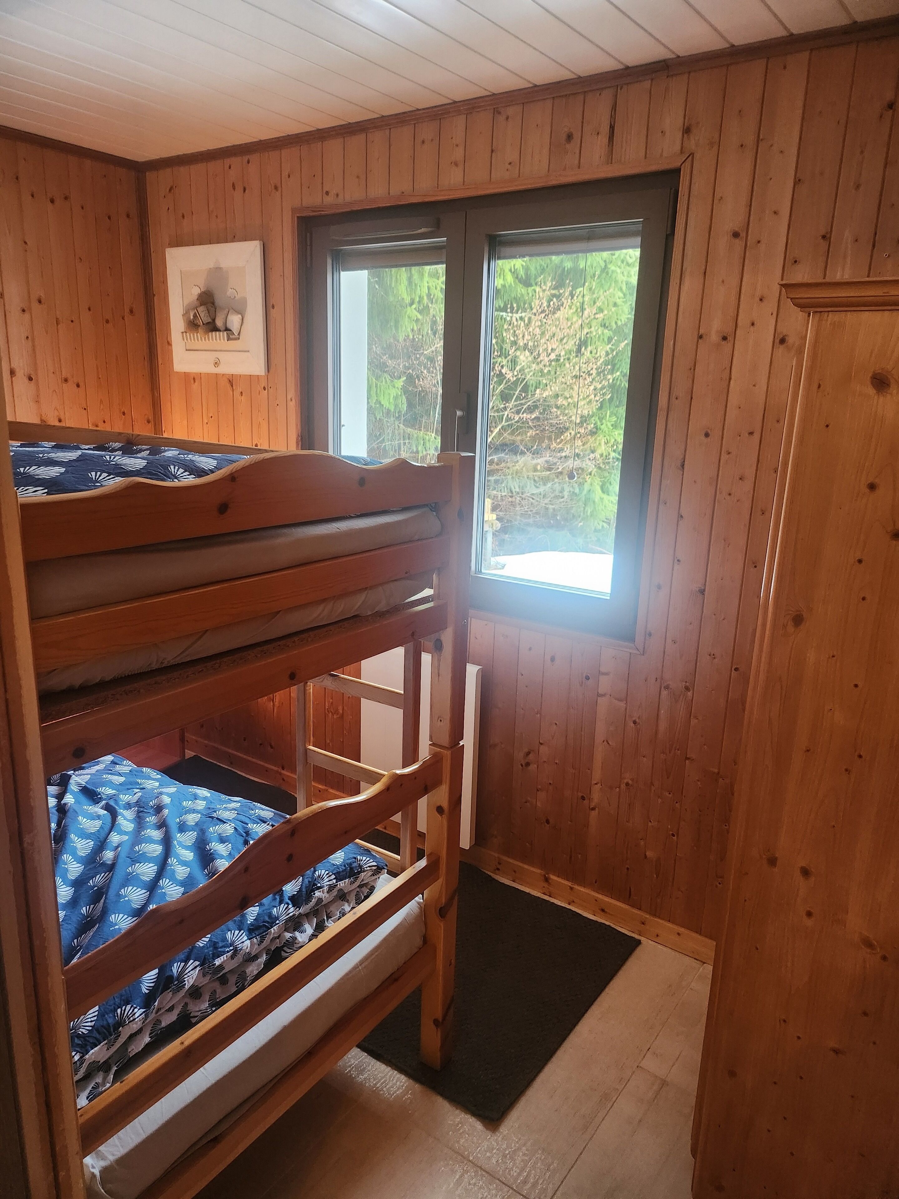 A bunk bed room with wooden walls and a window.