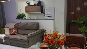 Un saló modern amb un sofà, una taula de menjador preparada amb plats i un ram de flors.