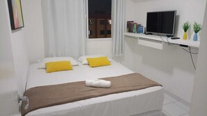 Habitació d'hotel ben ordenada amb un llit, una televisió i una finestra amb cortines.