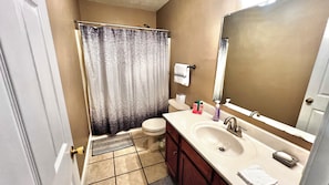 A bathroom with a toilet, sink, mirror, and shower curtain. - Spacious 3-Bed Townhome in Charming Somerset with the Ideal Location. (Somerset)