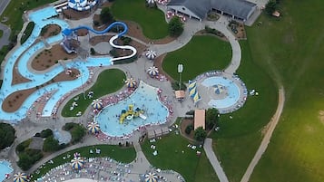 Vista aérea de un parque temático con diversas atracciones acuáticas, una plaza central y zonas verdes circundantes.