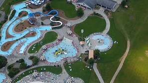 Oversigtsbillede af en forlystelsespark med forskellige vandattraktioner, et centralt torv og grønne områder omkring.