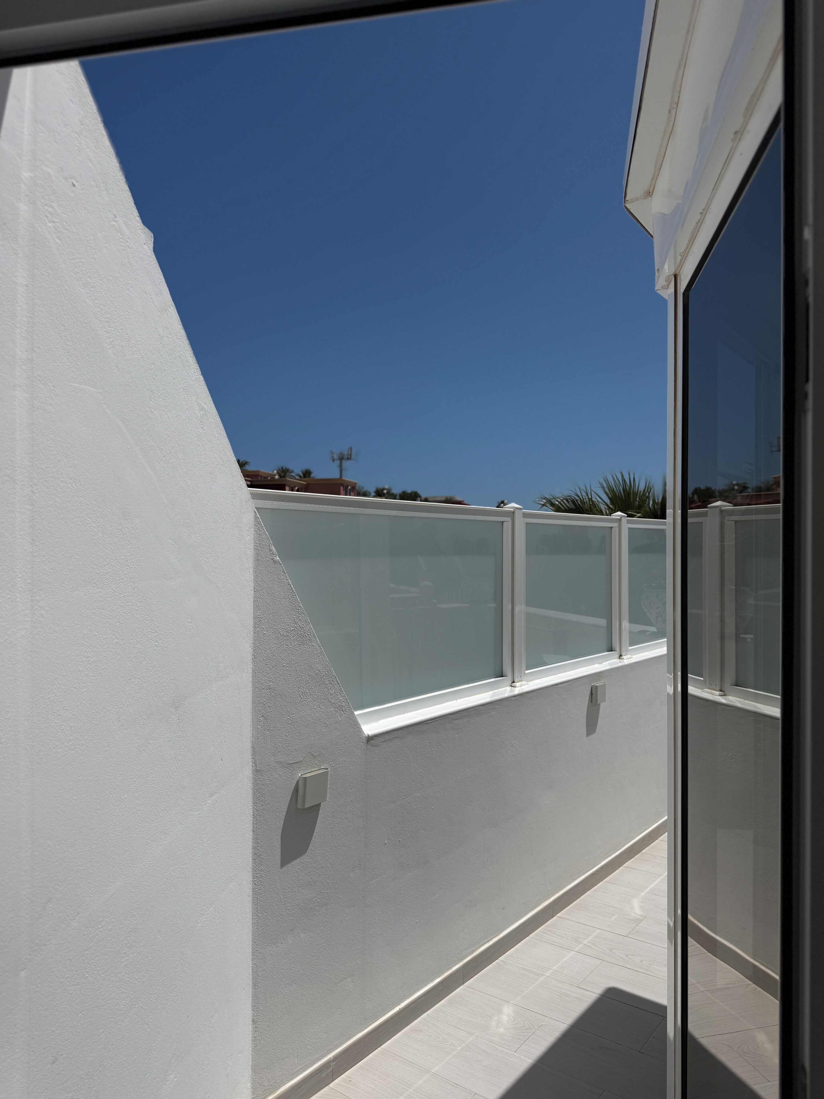 Ein modernes Gebäude mit hellem Himmel, weißer Wand und Glastür.