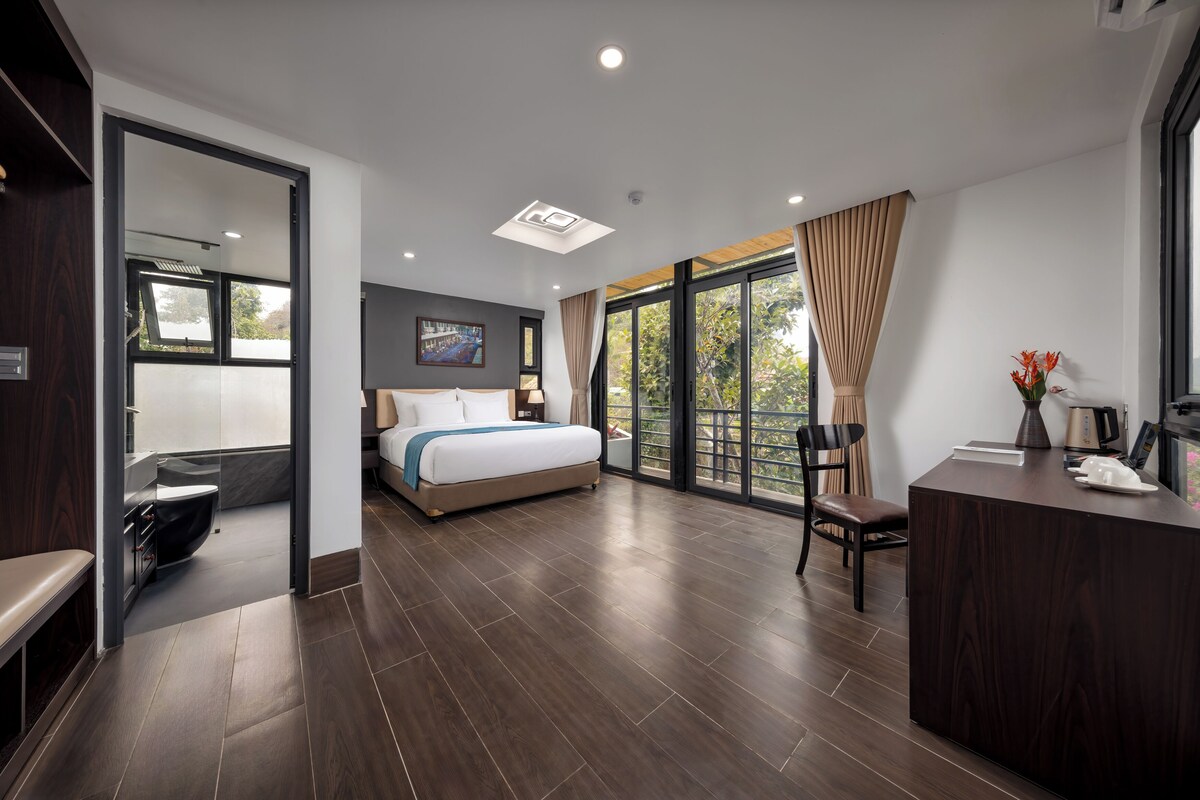 Une chambre d’hôtel moderne, dotée d’un grand lit, d’un bureau, d’une chaise et offrant une vue sur l’extérieur.