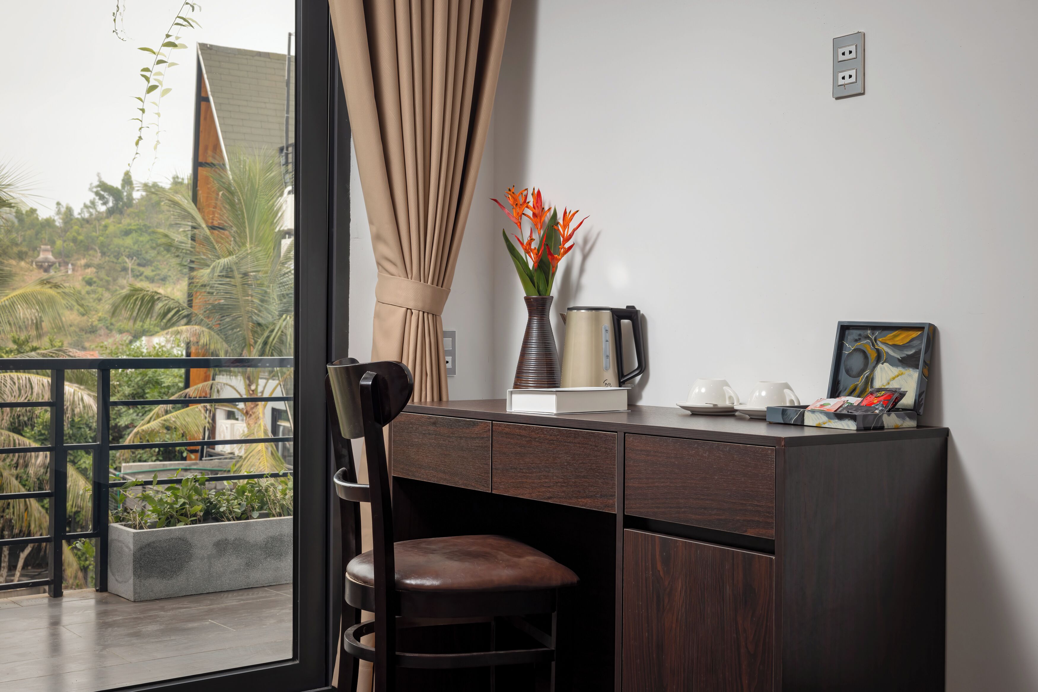 A modern room with a desk, chair, and a view of greenery outside.