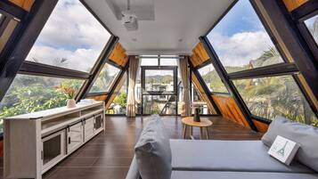 Una habitación moderna con una cama grande, una mesita y vistas al exterior a través de amplios ventanales.