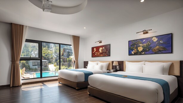 A hotel room with two beds, a large window with a view of a pool, and two paintings on the wall. - Cat Ba Sena Valley Retreat (Hai Phong)