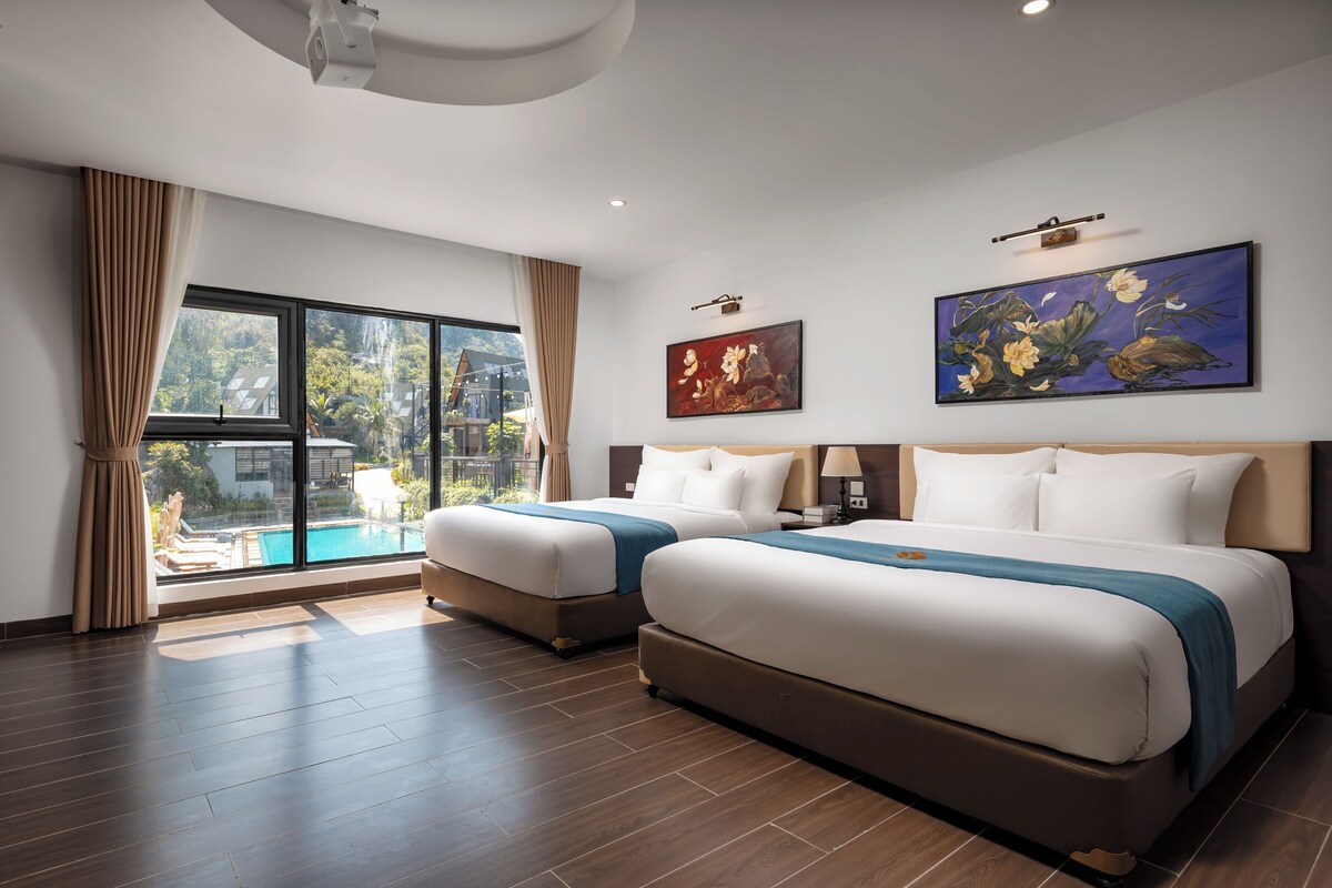Une chambre d’hôtel avec deux lits, une grande fenêtre donnant sur une piscine et deux tableaux accrochés au mur.