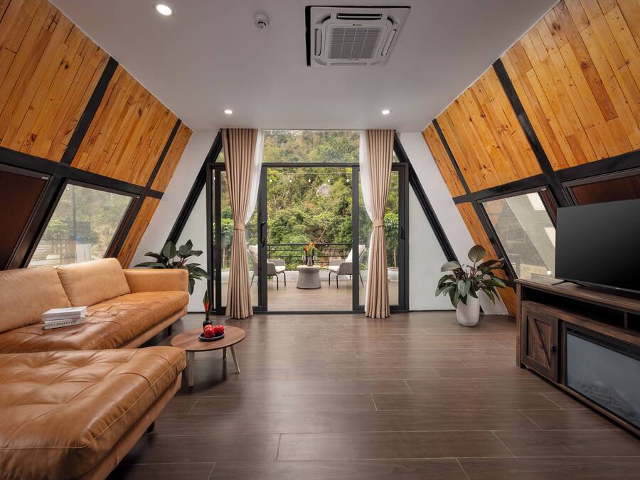 A modern living room with a leather sofa, a television, and a view of the outdoors.