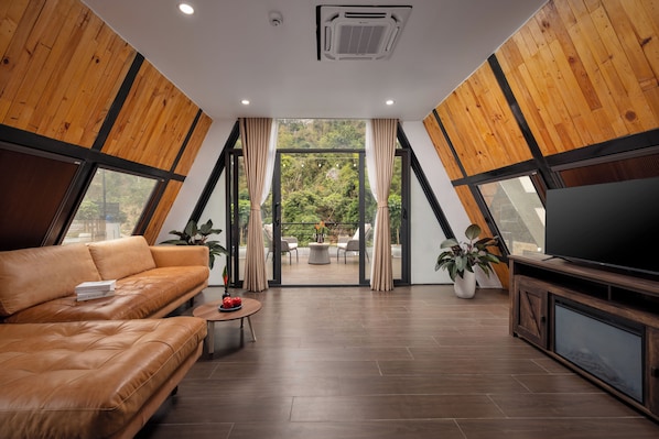 Ein modernes Wohnzimmer mit einer Ledersofa, einem Fernseher und Blick ins Freie.