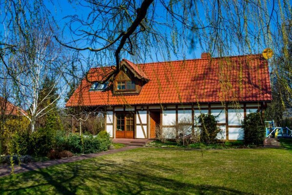 Une maison traditionnelle avec un toit recouvert de tuiles rouges, une porte en bois et une petite fenêtre.