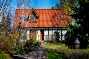 Ett tvåvåningshus med ett rött tegeltak, en väl synlig ytterdörr och en gångstig som leder fram till entrén.