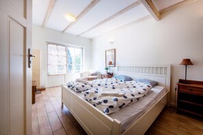 Une chambre à coucher avec un lit, une table de chevet, une lampe et une fenêtre.