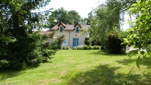 A house with a red-tiled roof, surrounded by lush greenery and a well-maintained lawn.