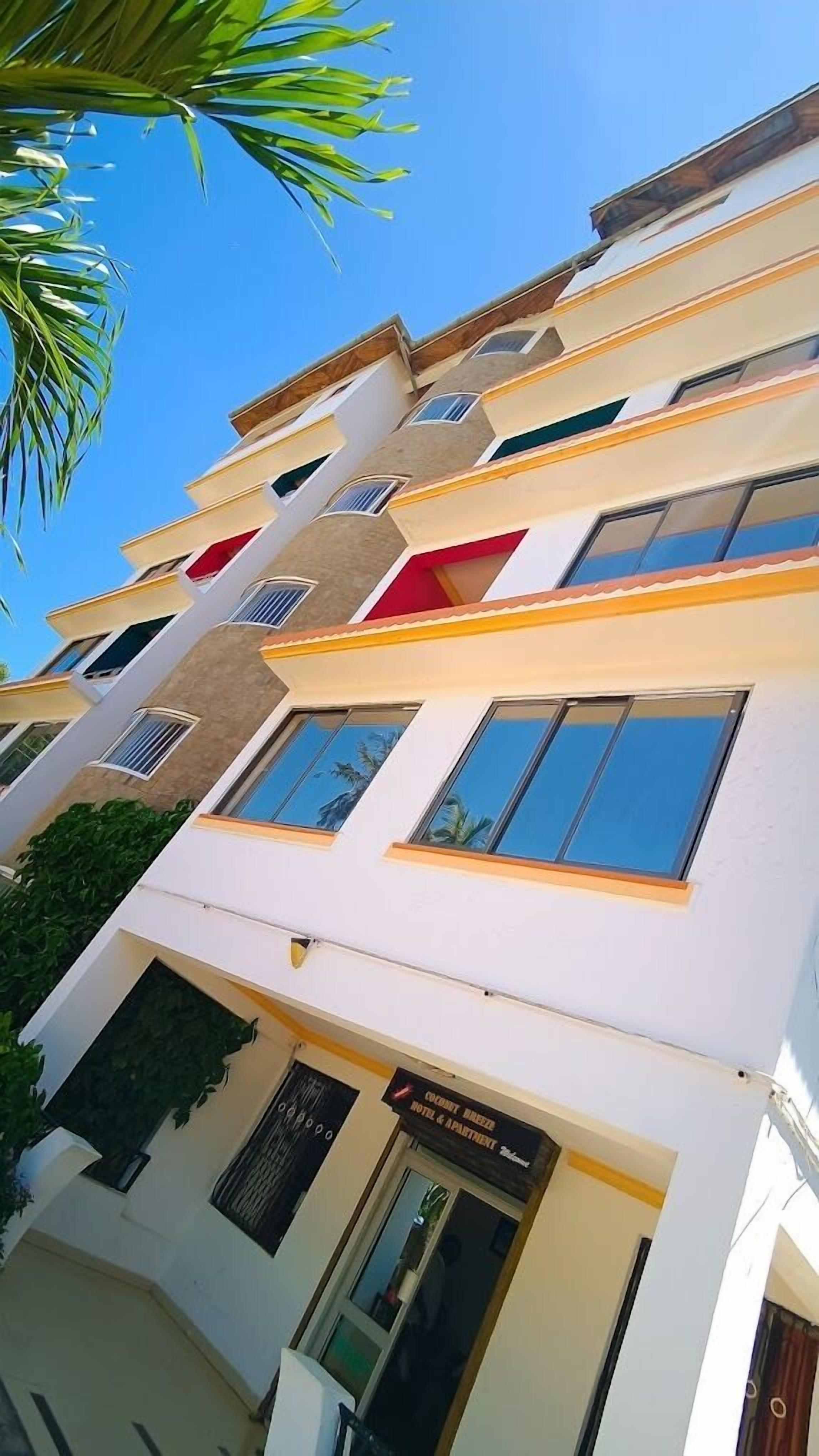 Un hotel de varios pisos con fachada blanca, múltiples balcones y un cartel que indica que es un edificio de hotel y apartamentos.