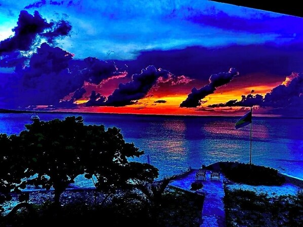 Atardecer sobre una masa de agua con una bandera en una pequeña isla.