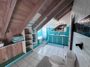 Un baño con techo de madera, inodoro blanco, lavamanos y espejo.