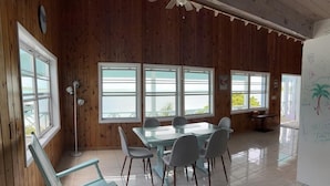 A room with a wooden paneled wall, a glass table with chairs, and large windows. - Cottage style living directly on the Ocean (Georgetown)