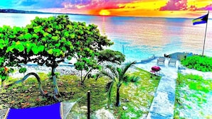 A beach view with a hammock, lounge chairs, and a flag. - Cottage style living directly on the Ocean (Georgetown)