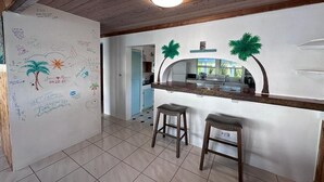 A kitchen with a whiteboard filled with drawings and notes, a wooden ceiling, and two stools. - Cottage style living directly on the Ocean (Georgetown)