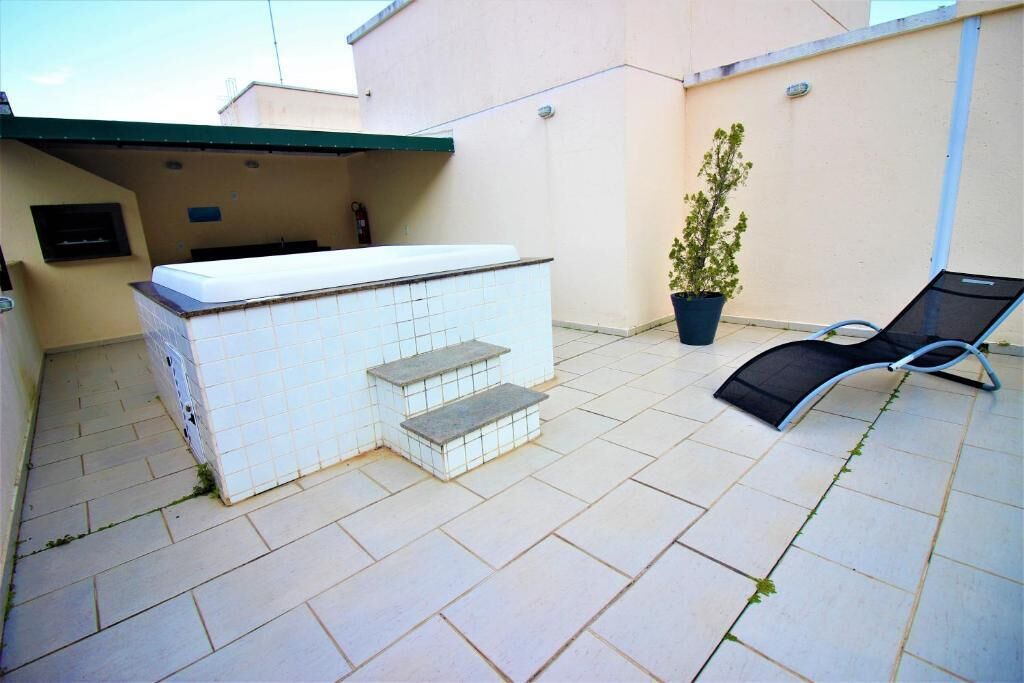 A patio area with a tiled barbecue station, a lounge chair, and a potted plant.