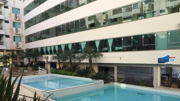 Een hotel met een groot overdekt zwembad, meerdere verdiepingen en balkons met airconditioning.