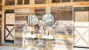 A rustic bathroom with wooden walls, two sinks, and two round mirrors.