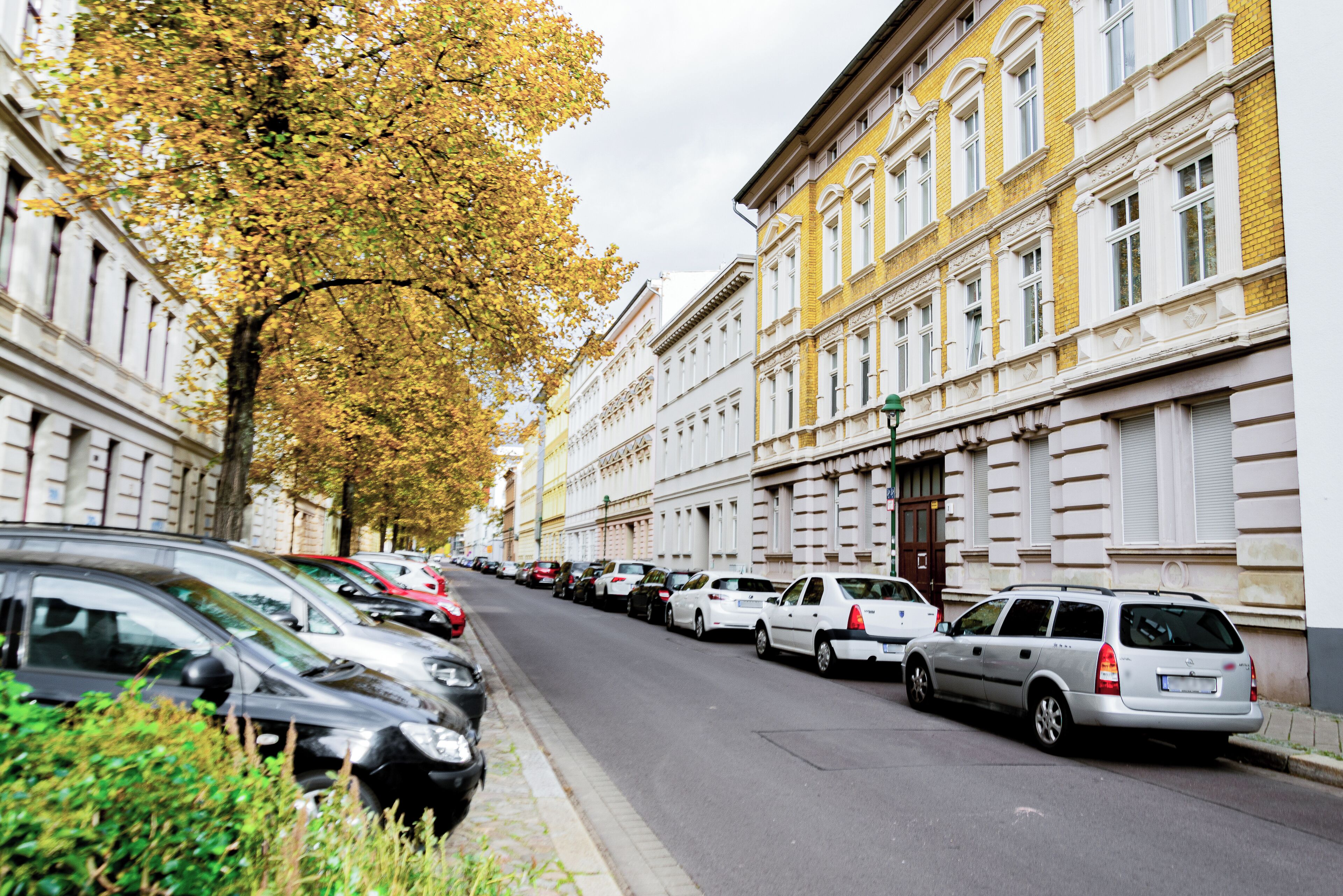 Une rue bordée de voitures garées et de bâtiments à l’architecture classique.