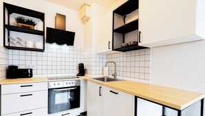 A modern kitchen with white cabinets, a wooden countertop, a built-in oven, and a black coffee machine. - Modern apartment with parking space & excellent connections - ideal for two (Magdeburg)
