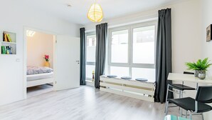 A modern, well-lit room with a bed, a desk, and a window with curtains. - Modern apartment with parking space & excellent connections - ideal for two (Magdeburg)