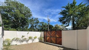 Un espace extérieur abrité, doté d’un sol en gravier et entouré d’un mur blanc agrémenté d’un panneau en bois.