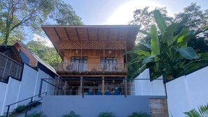 Un bâtiment à deux étages avec une façade en bois, un balcon et une allée gravillonnée.