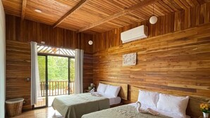 Une chambre avec deux lits, des murs en bois, un ventilateur de plafond et une fenêtre avec des rideaux.
