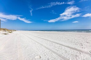 A wide sandy beach with a clear blue sky and a wooden boardwalk on the left. - Vitamin Sea Condo (Jacksonville Beach)